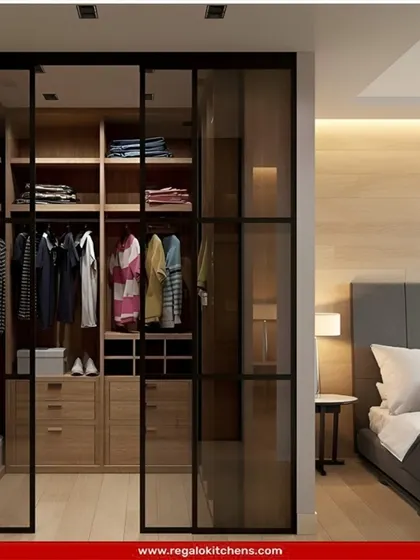 This wardrobe uses black-framed glass sliding doors to create a modern, industrial-inspired look that separates the closet from the bedroom while allowing light to pass through.