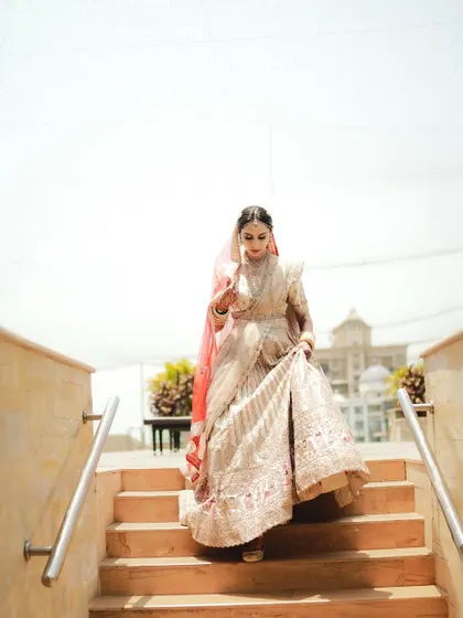 The bride's descent. A beautiful shot of the bride walking down the stairs, her lehenga gracefully held.