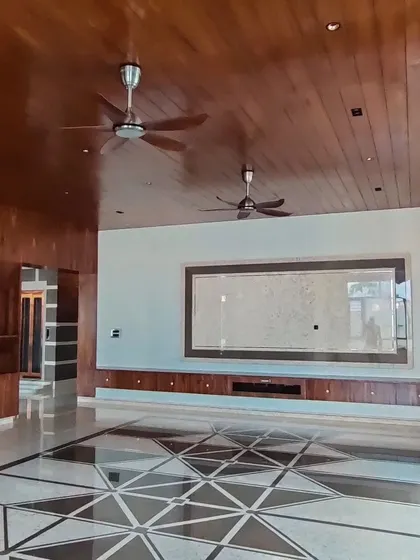 Another view of the large living space, showing the built-in wooden console under the TV area and the geometric marble floor inlay.