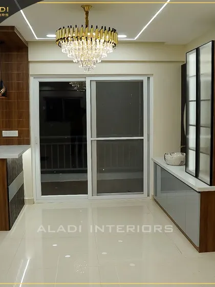 An open-plan area showing the kitchen, dining space, and living room. The consistent use of wood, white, and a magnificent chandelier ties the entire space together.