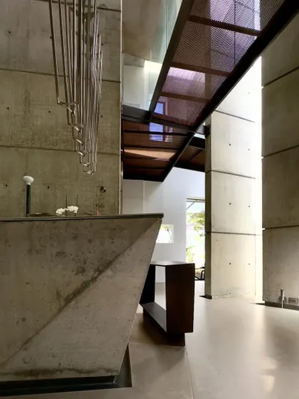The main living area of the 'House of Stories' project, where a custom concrete console and sculptural steel elements interact with the tall, light-filled volume. The design is an exercise in minimalism, allowing the architecture itself to be the primary feature.