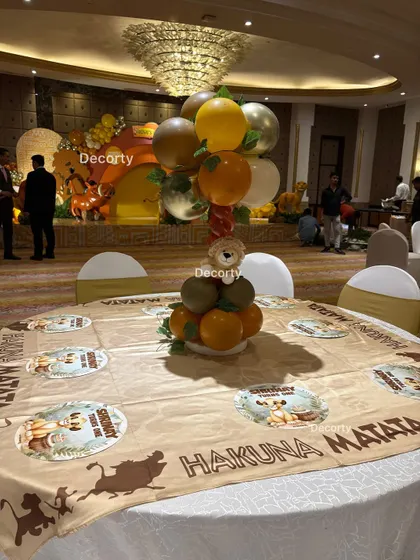 A full view of a guest table at the Lion King party, showing the themed tablecloth and a balloon centerpiece, with the main stage in the background.