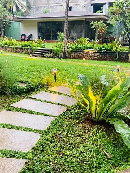 A stone pathway meanders through the lawn, dotted with subtle landscape lighting that provides safe passage and a gentle glow in the evening.