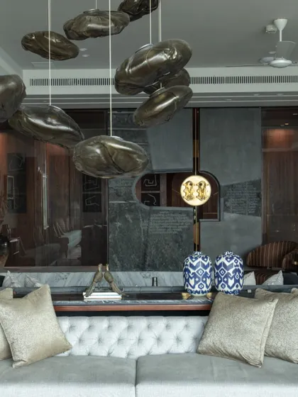 A textured stone wall in the living room serves as a backdrop for charcoal art by Paresh Maity and a piece by Jogen Chowdhury. The space is a curated gallery of master artists, reflecting the client's passion for collecting.