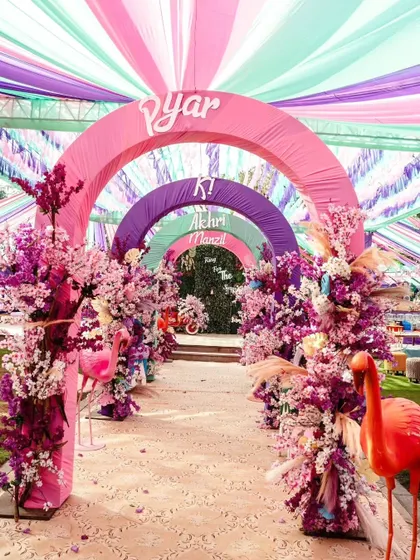 Step into a world of pure joy with an entrance that sets a vibrant tone. We design immersive experiences like this colorful arched walkway, using fabric draping and floral arrangements to build excitement from the very first moment.