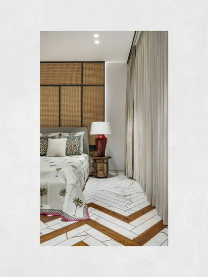 In the parent's room at Kamala Residence, we elevated simple marble flooring by creating a herringbone pattern with wooden inlays. A rattan headboard continues the home's tropical theme.