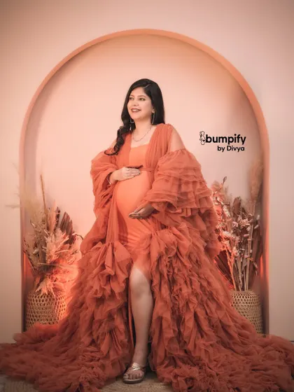 A confident and radiant solo pose. The mom-to-be glows in the orange gown, a perfect celebration of her strength and beauty during pregnancy.