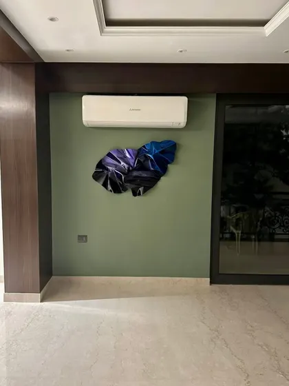 The wider view shows how the sculpture's minimal presence complements the room's dark wood and olive green walls.