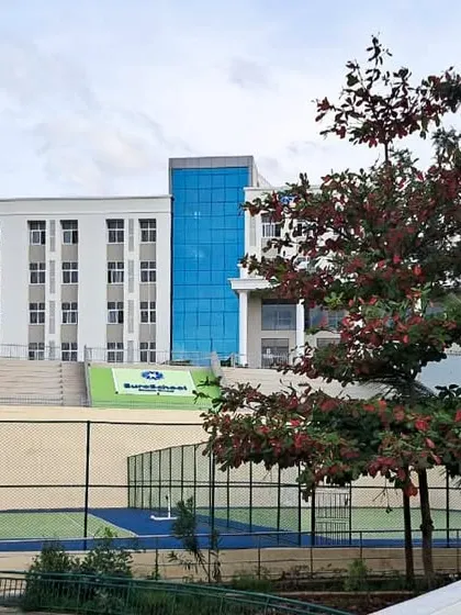 A view of the EuroSchool campus showing the main building in context with the outdoor sports court. This highlights our planning for integrated indoor and outdoor student activities.