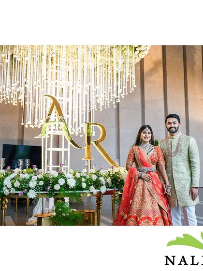 The happy couple at their engagement. The grand floral chandelier and personalized monogram create a backdrop that is both luxurious and deeply personal.