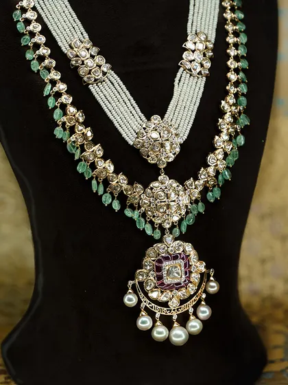 This layered necklace is everything a bride could dream of. Polki detailing, emerald drops, and pearls come together with a stunning ruby accented pendant, perfect for when you want to feel like royalty.