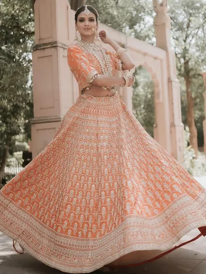 A graceful twirl in a peach-colored lehenga with intricate white embroidery. This is a perfect choice for an engagement or a summer wedding.