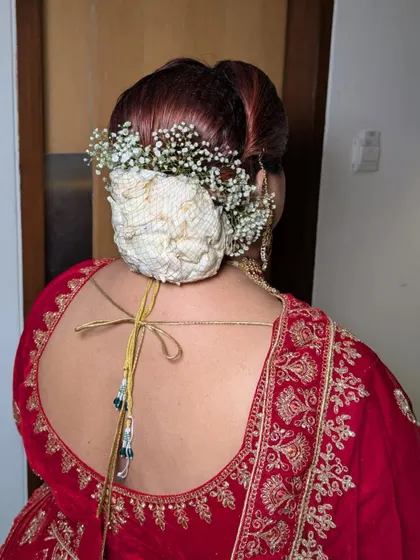The bridal bun is adorned with a traditional 'gajra' made of fabric and baby's breath, a unique twist on a classic hairstyle.