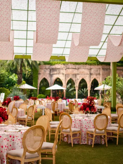 The dining setup for the Mehendi lunch, with custom floral-printed tablecloths and red centerpieces under a canopy of draped fabric.