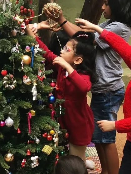 Children of all ages come together to decorate the Christmas tree. Each child adds an ornament, contributing to a beautiful, shared creation that marks the festive season.