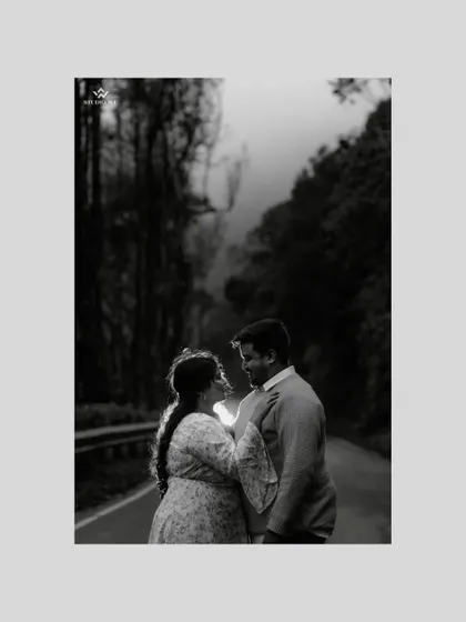 A moody, black and white shot of a couple on a foggy road surrounded by trees. This artistic choice adds a timeless and cinematic quality to their pre-wedding story.
