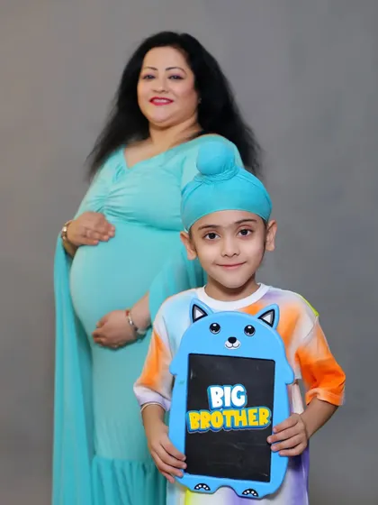A proud "BIG BROTHER" poses with a cute sign in front of his expectant mother during their family maternity session in our studio.