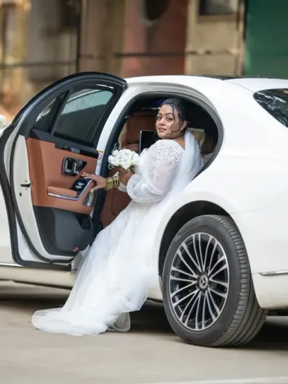 A grand entrance for a stunning bride. Stepping out of a luxury car, she looks every bit the modern princess on her wedding day.