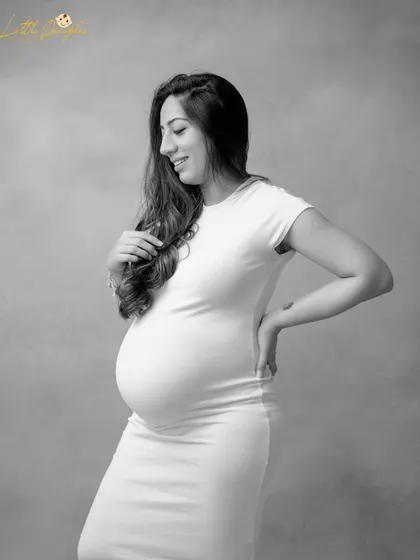 A timeless and simple black and white portrait. The focus is all on her happy expression and the beautiful curve of her baby bump.