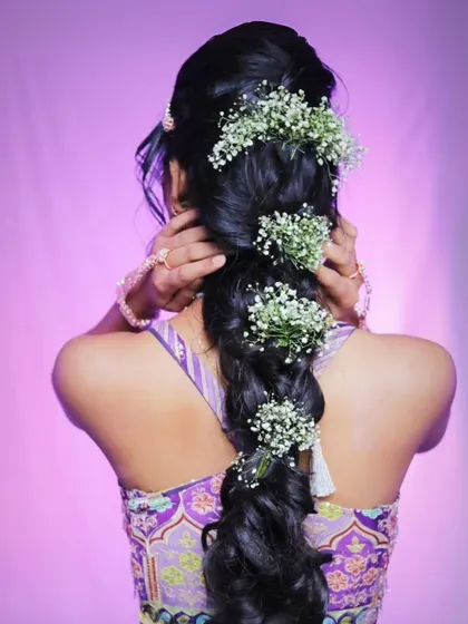 A detailed shot of the beautiful braided hairstyle, adorned with delicate baby's breath flowers for a touch of whimsy.