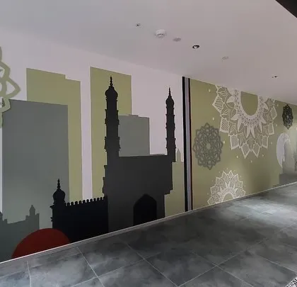 A wider view of the Hyderabad-themed abstract mural, showing how it covers a long wall in the cafeteria breakout area.