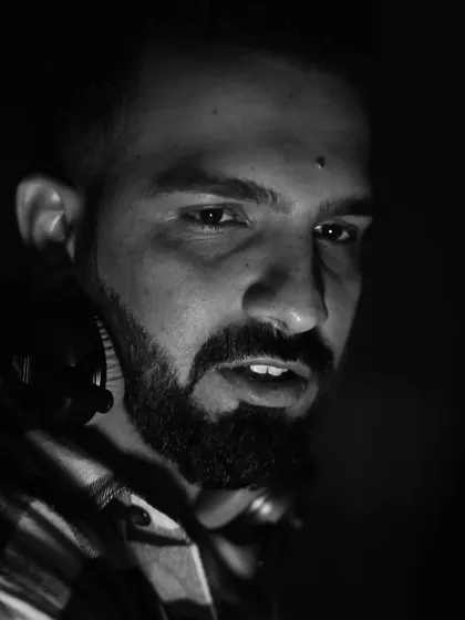 An intense, close-up black and white portrait. This is the focused look of a DJ who is deep in the mix.