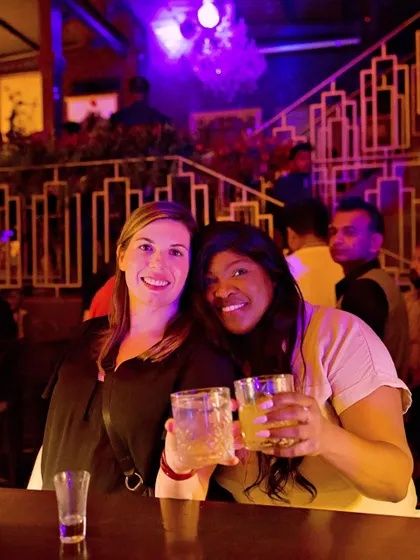 Two guests toasting with their drinks, enjoying the Saturday night party.