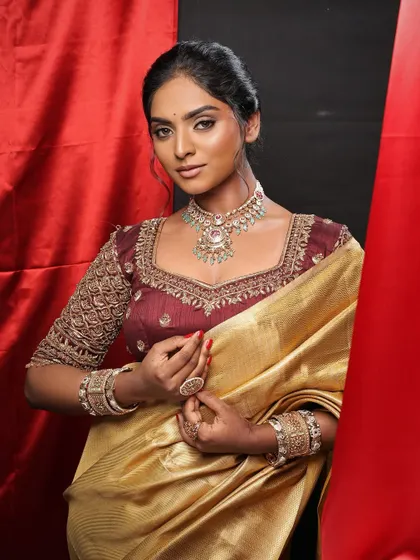 The rich colors of the saree and blouse are beautifully complemented by the warm, earthy tones of the makeup.