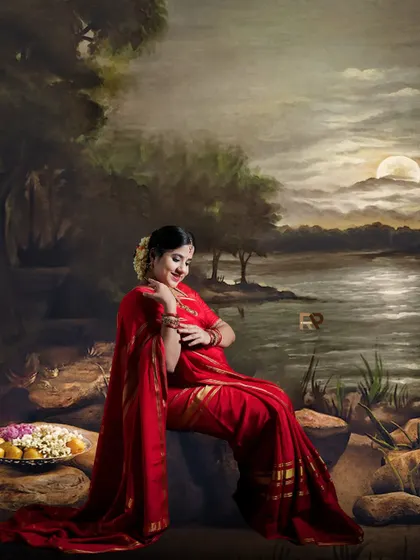 A serene moment of reflection. The mom-to-be is seated gracefully, her red saree draped beautifully around her, with a platter of offerings adding to the traditional ambiance.