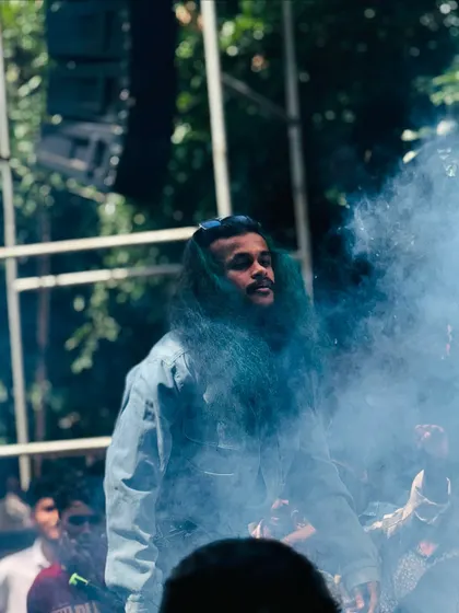 Surrounded by a cloud of smoke on stage, creating a dramatic entrance at a college DJ night.