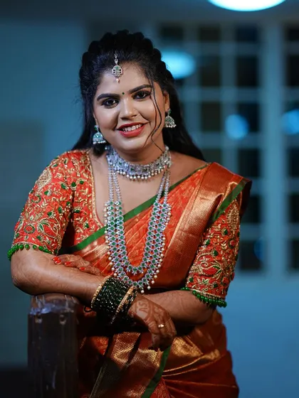 The bride looking radiant in her orange and green reception saree with a heavily embroidered custom blouse.