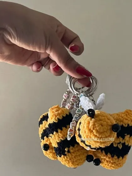 Holding a bunch of the bee keychains to show how they look as a set. The combination of the yellow and black yarn with the white wings is so classic.