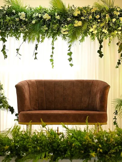 A simple and modern engagement stage with a lush arch of greenery and white flowers, creating a tropical yet elegant feel.