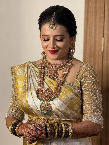 This bride looks serene and beautiful on her wedding day. The intricate gold embroidery on her blouse adds a touch of luxury to her classic bridal ensemble.