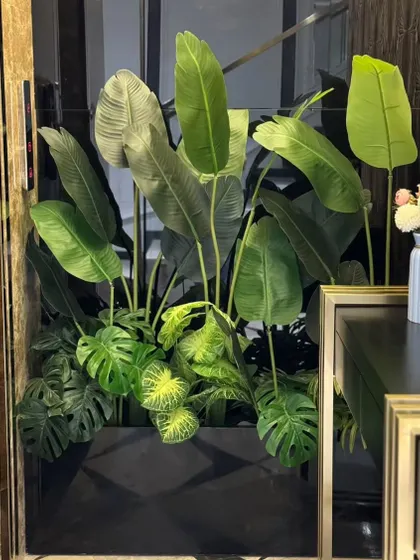 A lush arrangement of artificial tropical plants, including Bird of Paradise and Monstera, fills an awkward niche. This zero-maintenance solution brings vibrant, year-round greenery to a modern interior.