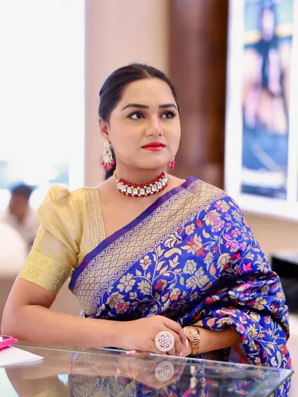 A different pose in the blue saree, showcasing its rich texture and the elegant puff-sleeve blouse.