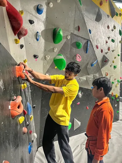 Learning to climb is a journey we take with you. Here, one of our instructors provides one-on-one guidance to a young climber, explaining the route and technique. Our introductory sessions focus on basics, balance, and having fun.