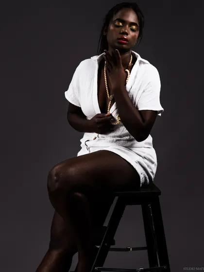 A conceptual, low-key portrait of a model with dark skin in a white outfit, creating a stunning visual contrast. This artistic series explores themes of light, shadow, and beauty.