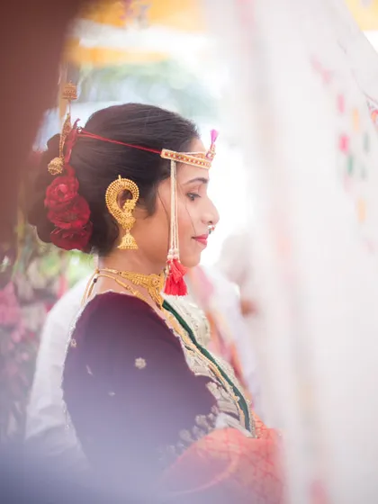 A beautiful side profile of the bride, Priyanka, captured through the Antarpat cloth just before the wedding ceremony begins.