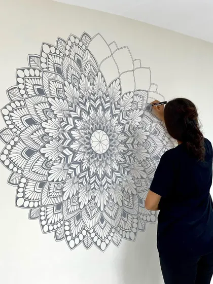 Adding the final details to a large grey and white mandala mural. This piece was designed to be a subtle yet captivating feature in a minimalist home.