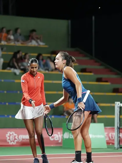A candid moment of on-court communication between doubles partners during a competitive match.