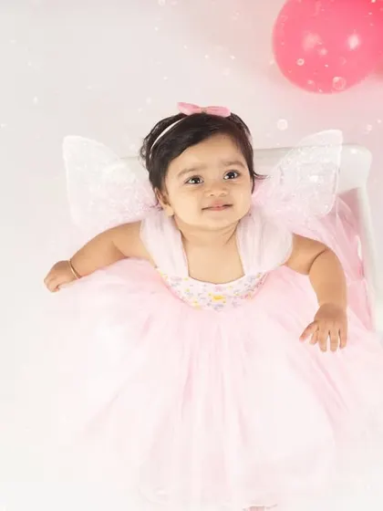 A little fairy in a snowy wonderland. The delicate wings and pink dress make for a magical and dreamy first birthday portrait.