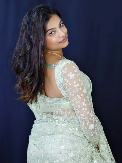 A back view of Sonu in the mint green saree, showing the sheer, embroidered full sleeves of the matching blouse.