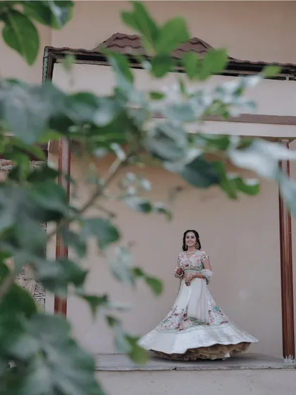 An artistic shot of the bride framed by green leaves, creating a natural and soft portrait.
