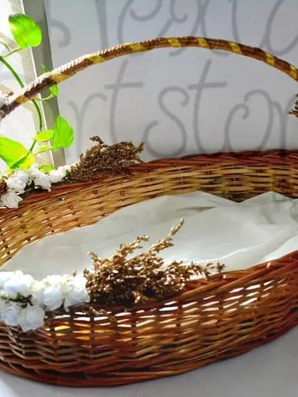 This is an example of a custom-decorated hamper basket, perfect for weddings or special events. The sturdy oval cane basket is adorned with flowers and lined with fabric, ready for gifting.