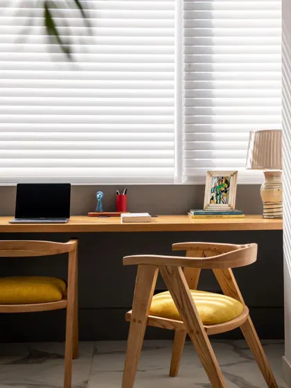 We reinvented this space by transforming a balcony into an innovative study alcove. The long wooden desk provides ample workspace for two, while natural light filters through the blinds, creating a warm and productive atmosphere.