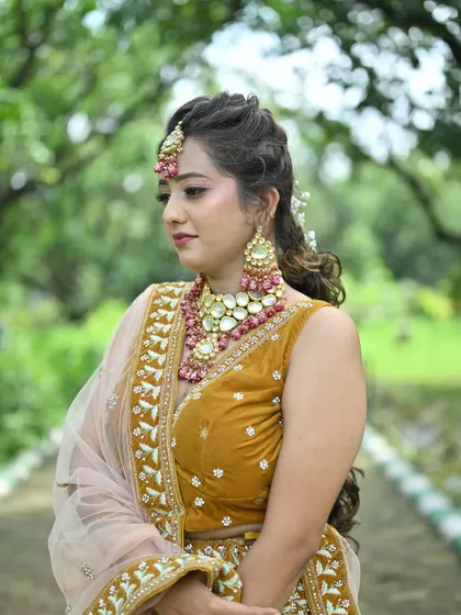 A close-up of the mustard yellow lehenga, focusing on the intricate blouse embroidery and the beautiful pink and gold jewellery.