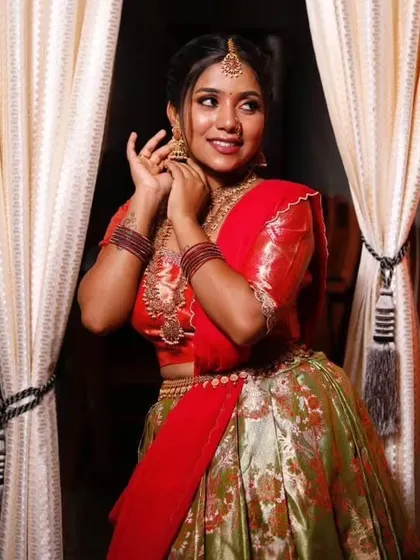 A client looking beautiful in a green and red traditional half saree, perfect for a festive occasion or a wedding.