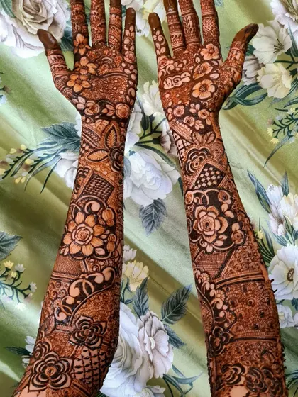A gorgeous floral-heavy bridal design for the bride Hani. The patterns are dense and intricate, covering the hands and arms completely.