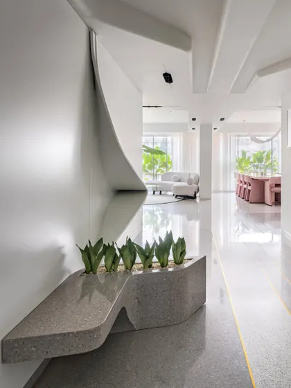 The entrance of Apartment 56 is designed as a seamless flow of finishes and forms. Petal-like ceilings, dynamic lights, and custom-built planters guide you away from a narrow corridor and into the expansive, light-filled living spaces.